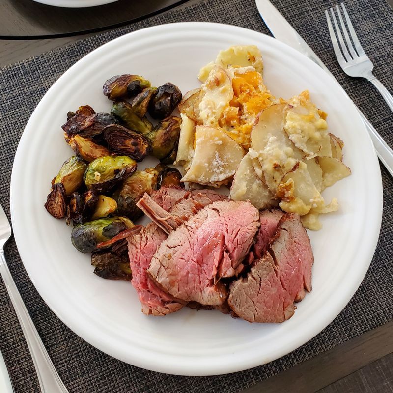 A white plate topped with sliced filet mignon and vegetables on a table