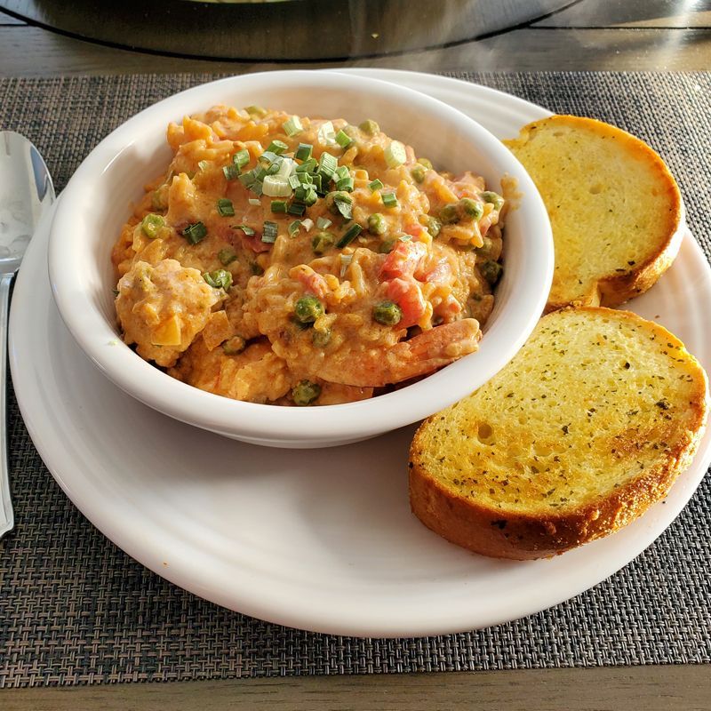 A white plate topped with a bowl of Shrimp Orzo and garlic bread