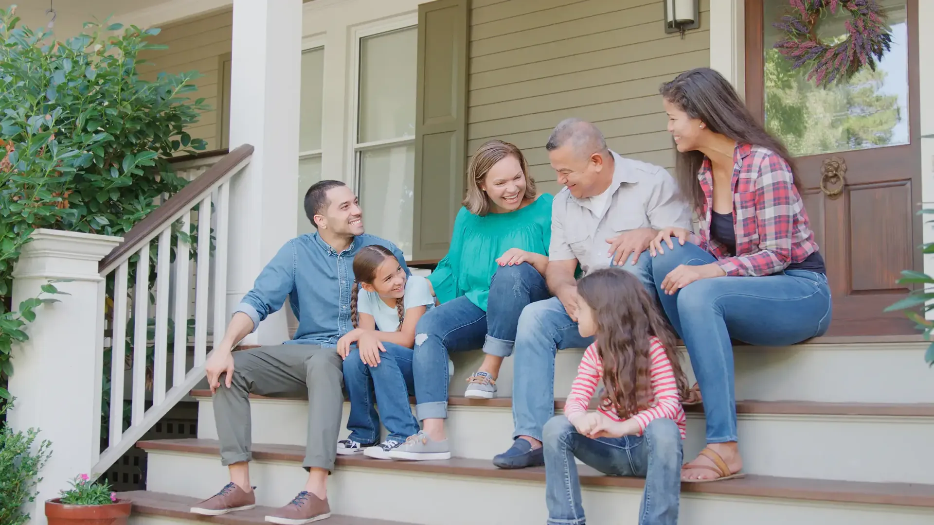 Family sitting on porch steps, smiling and interacting.