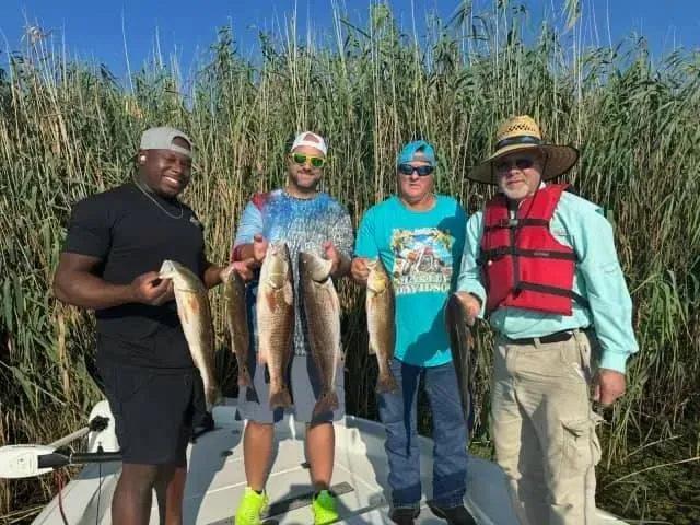 A group of men are standing on a boat holding fish.