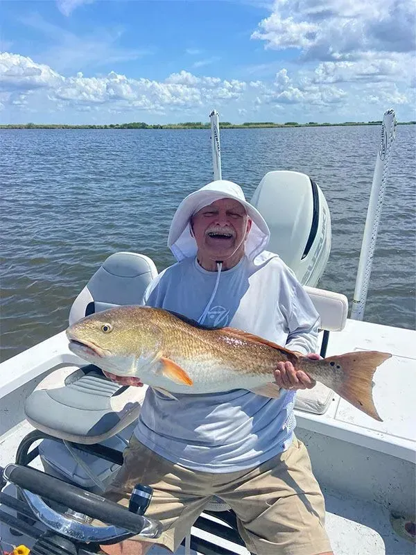 A man is sitting on a boat holding a large fish.