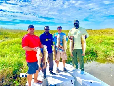 A group of men are standing on a boat holding fish.