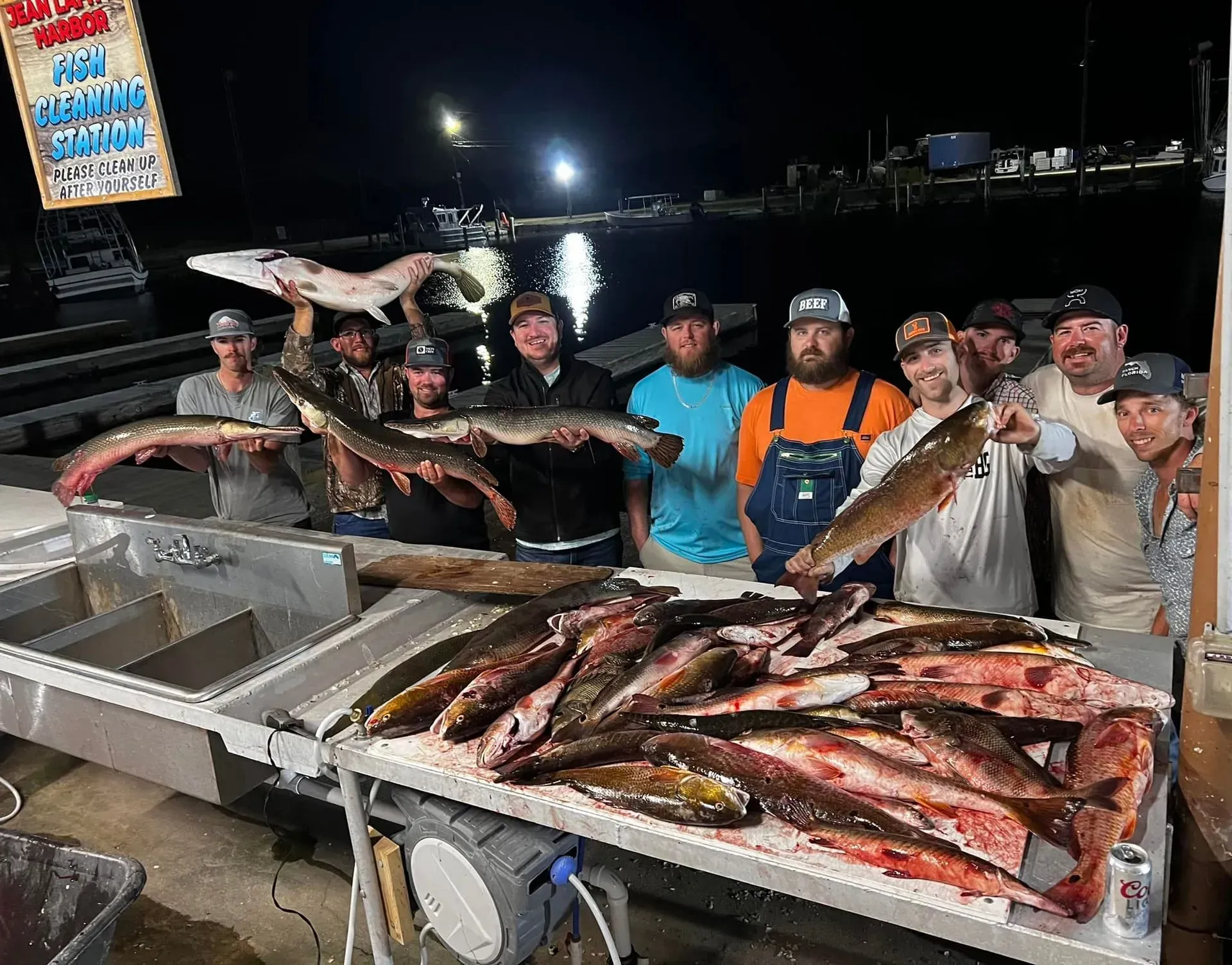 A group of men are standing around a table holding fish.