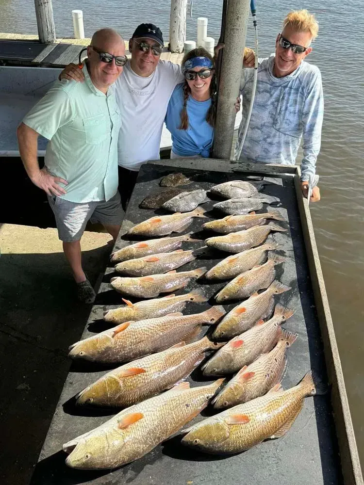 Four people and a table full of fish caught fresh

