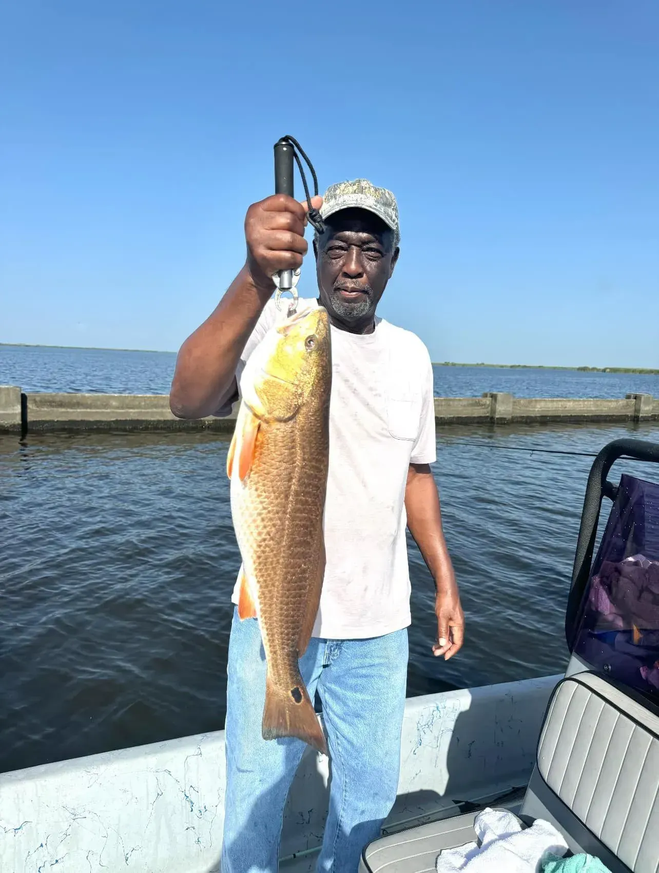 A man is standing on a boat holding a large fish.