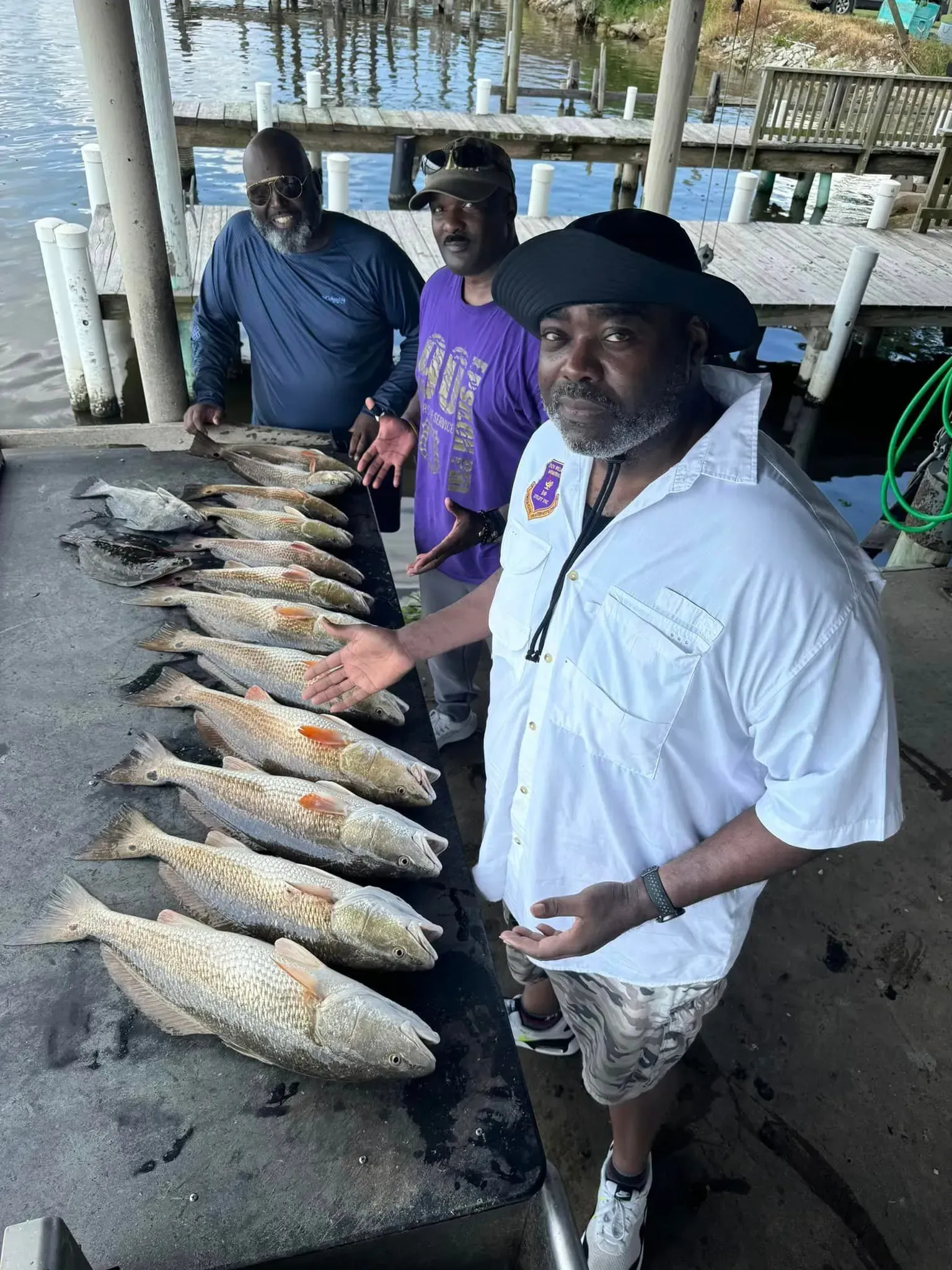 3 men showing off their catch on a table
