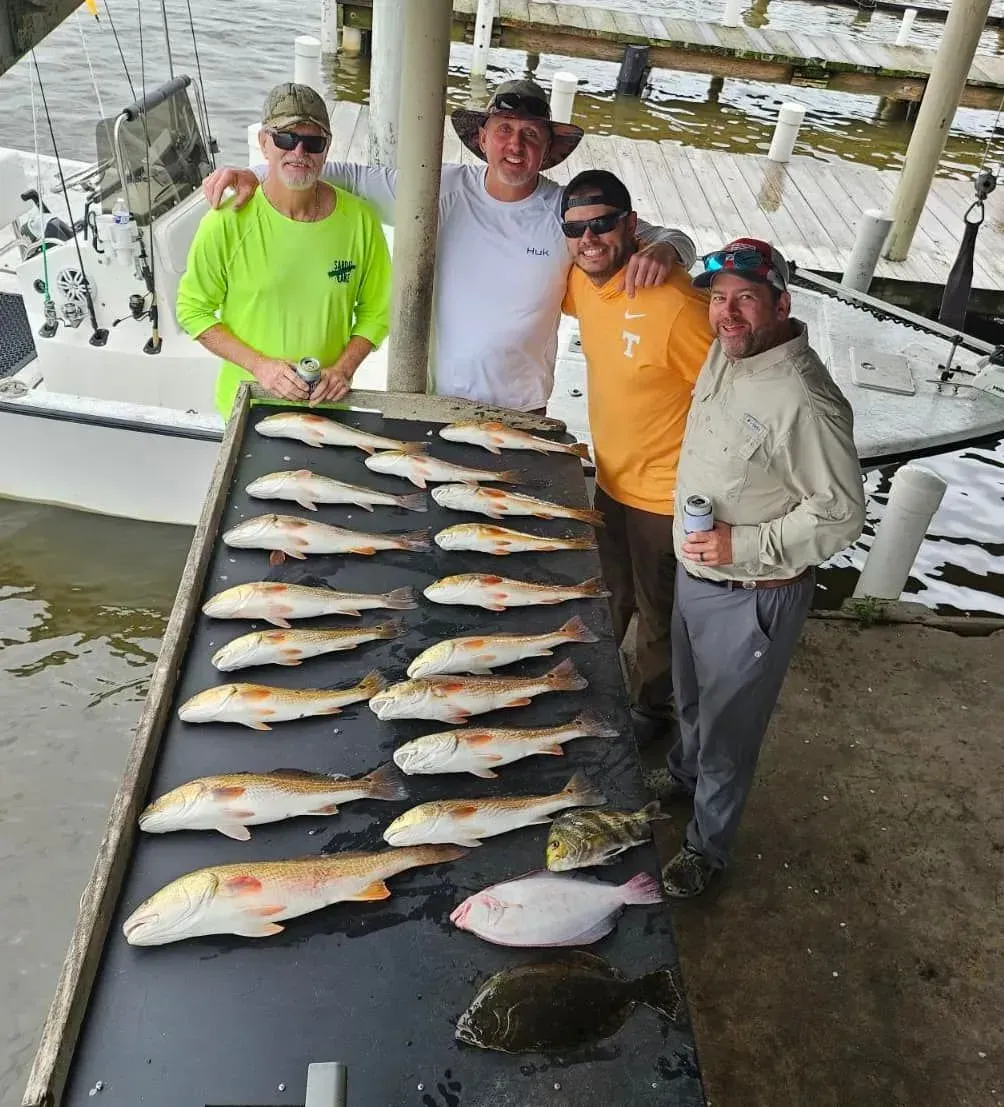 Four people with a table full of fish
