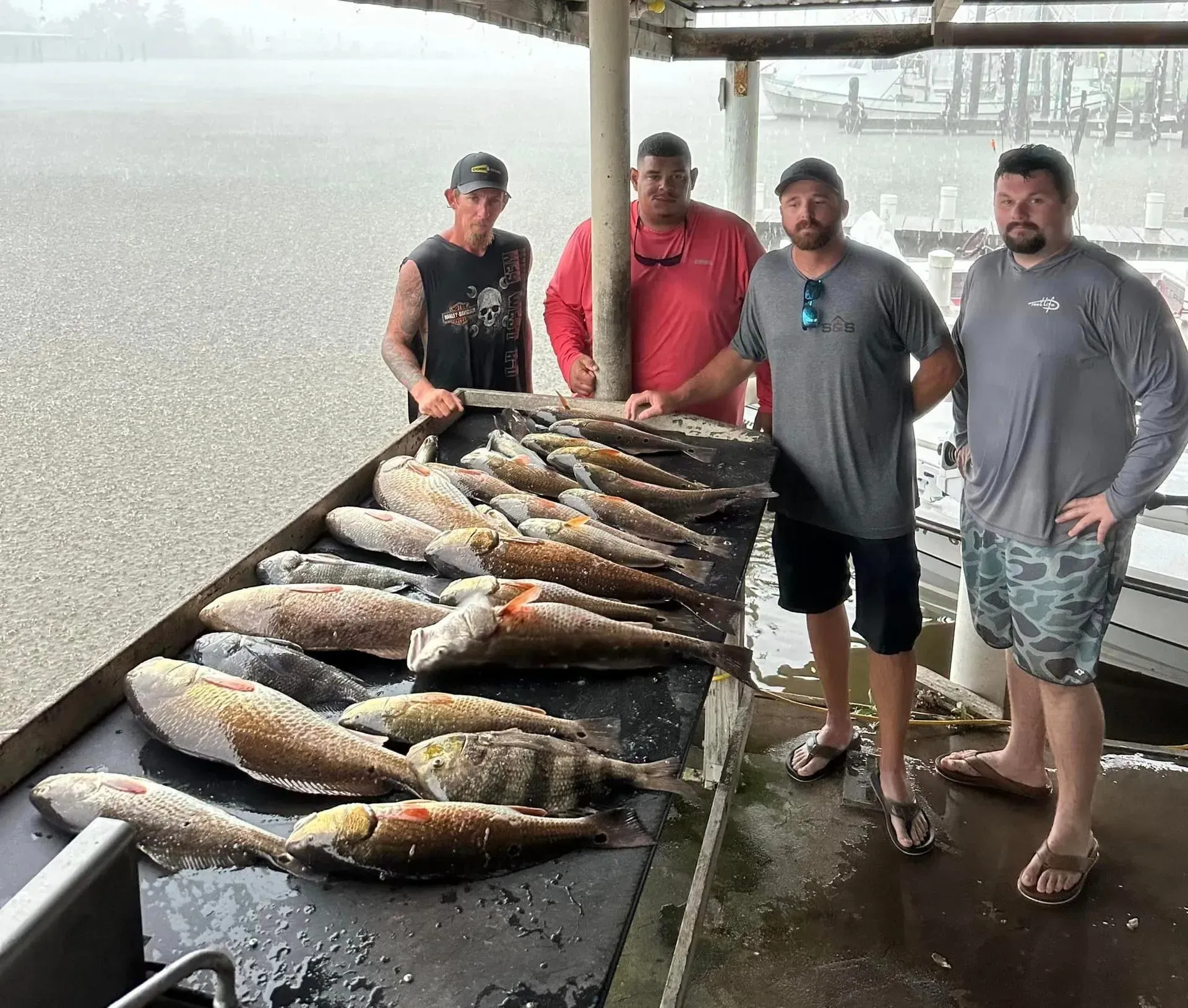 A group of men are standing next to a table full of fish.