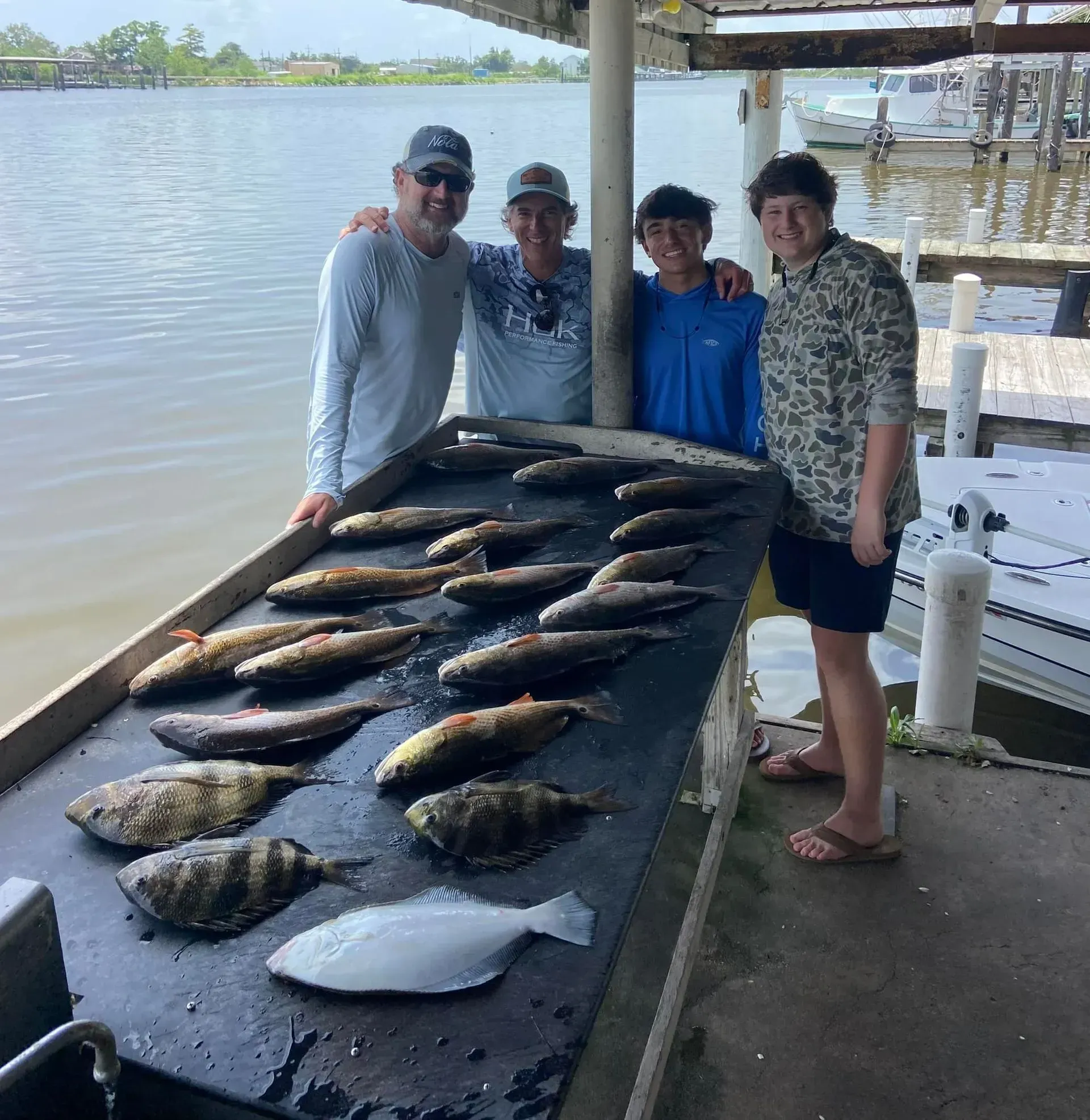 Three men standing next to a table full of fish.