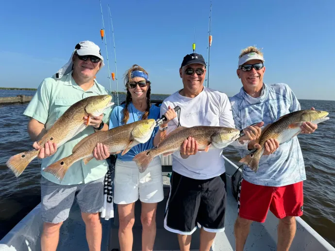A group of people are standing on a boat holding fish.