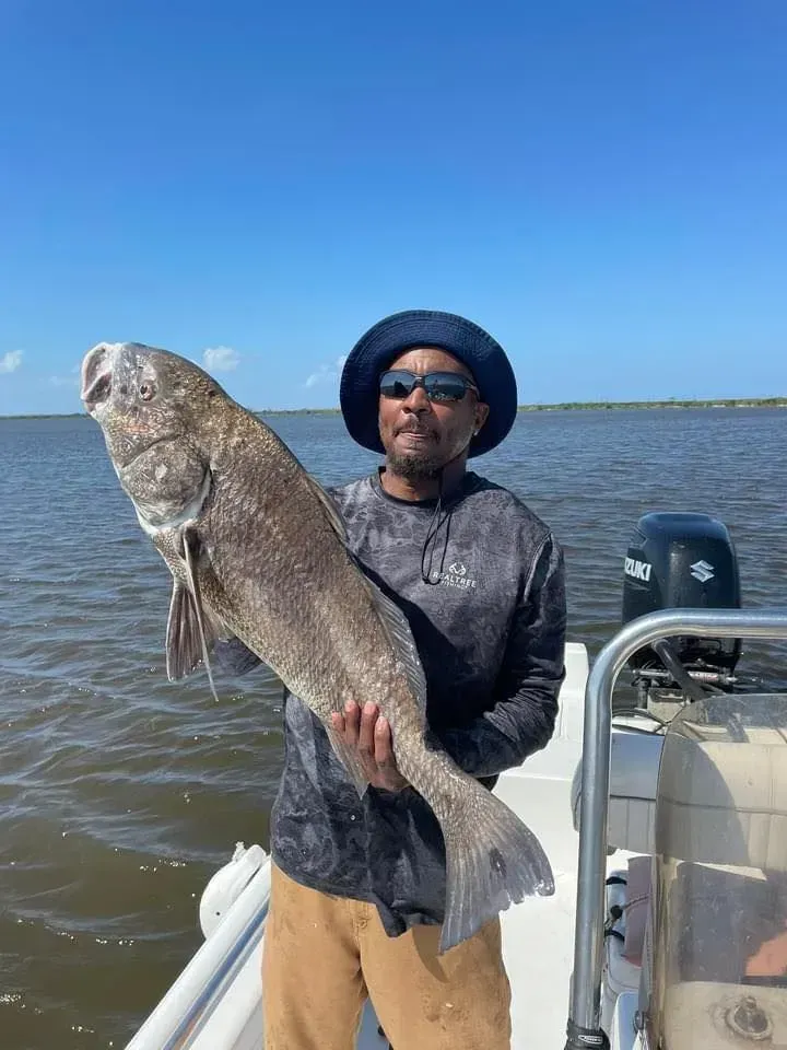 A man is holding a large fish on a boat.