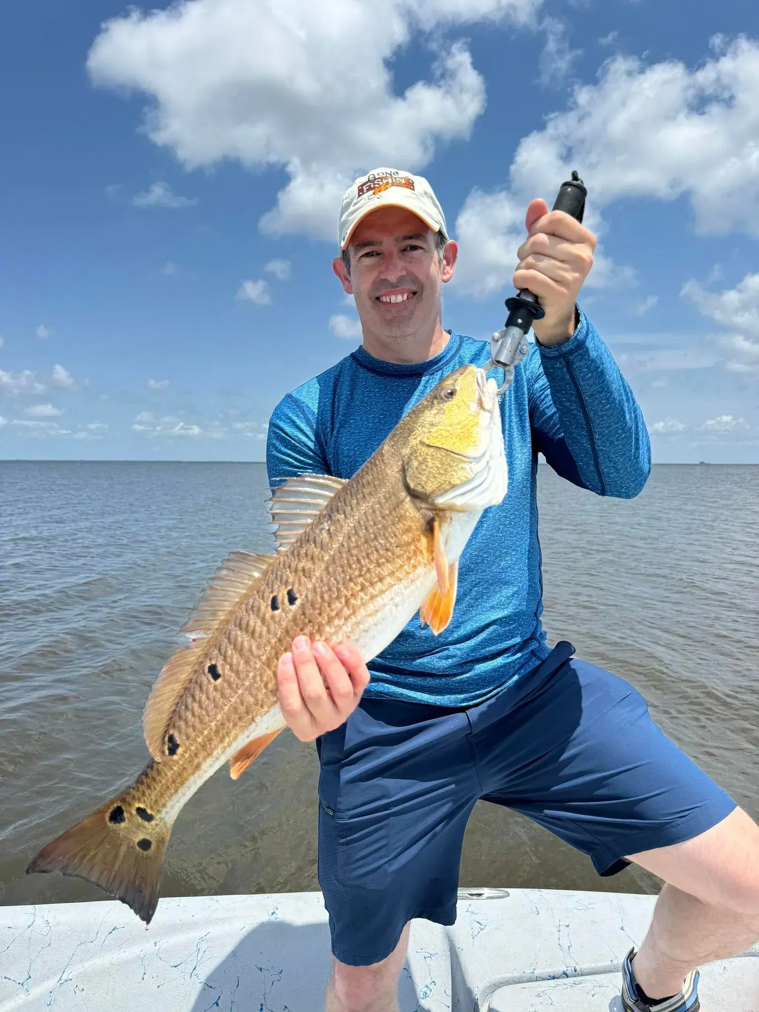 A man is holding a large redfish on a boat.