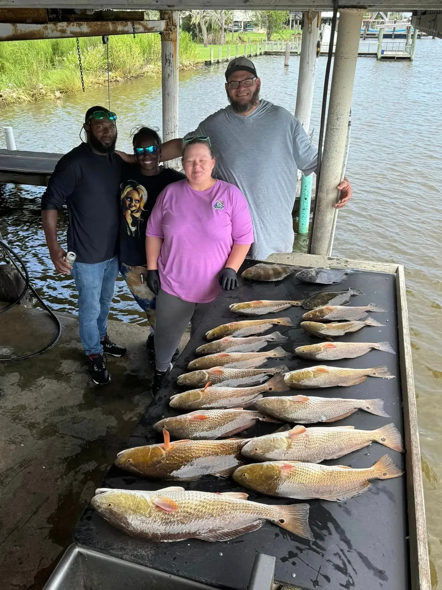Four people with a table full of fish
