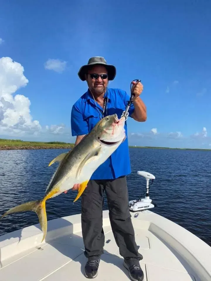 A man is holding a large fish on a boat.