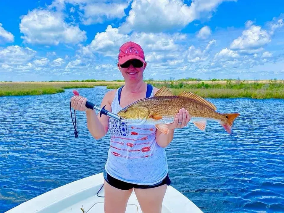 A woman is standing on a boat holding a large fish.