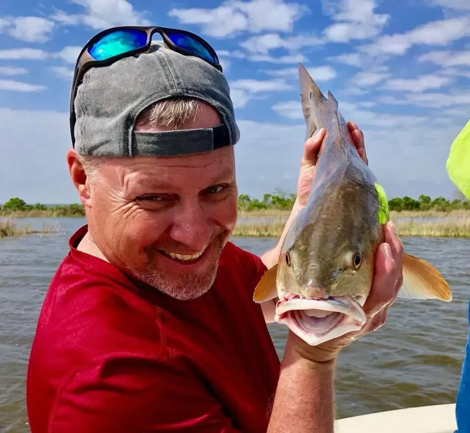 A man is holding a fish in his hands and smiling.