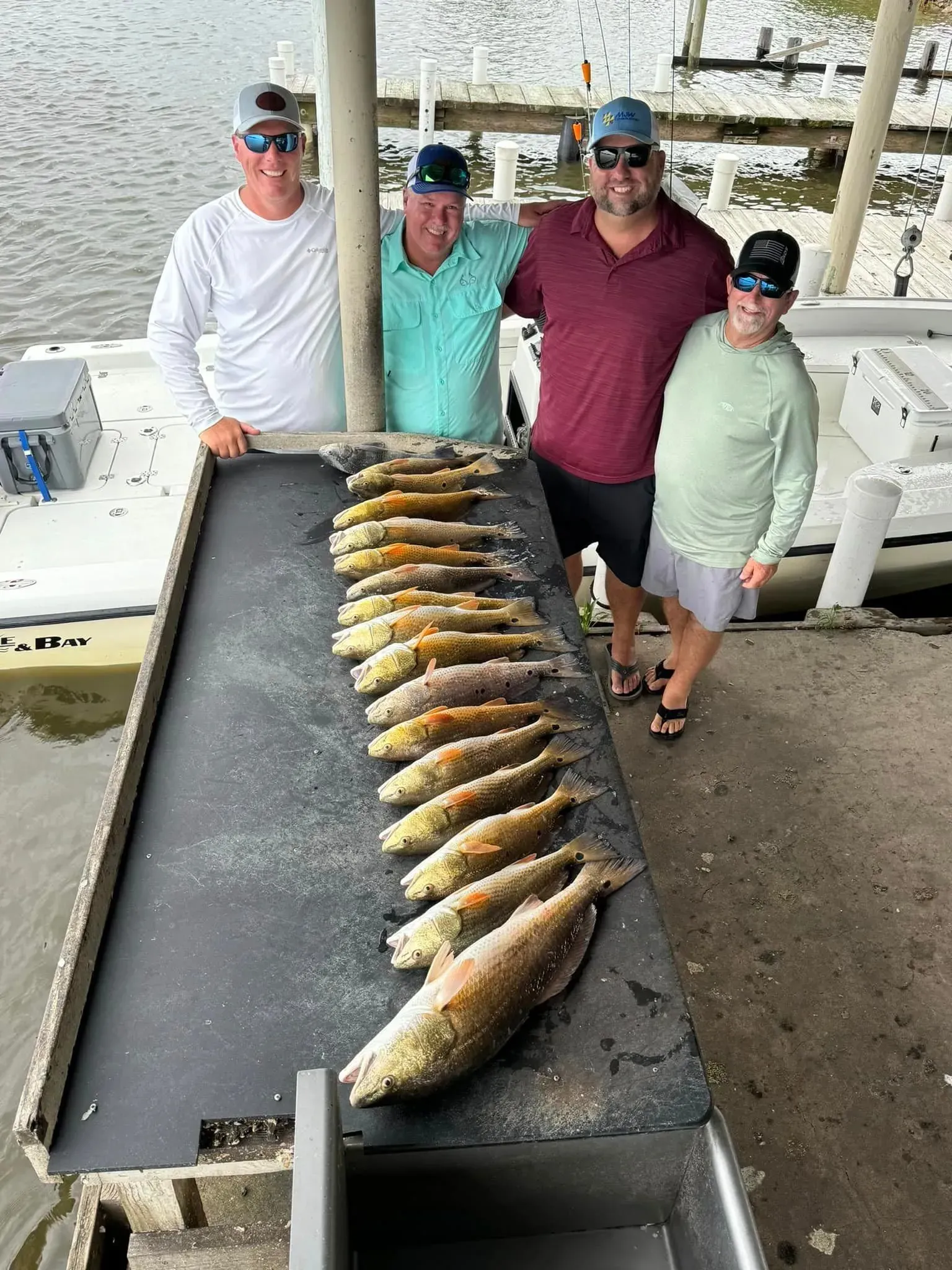 A group of men are standing next to a table full of fish.