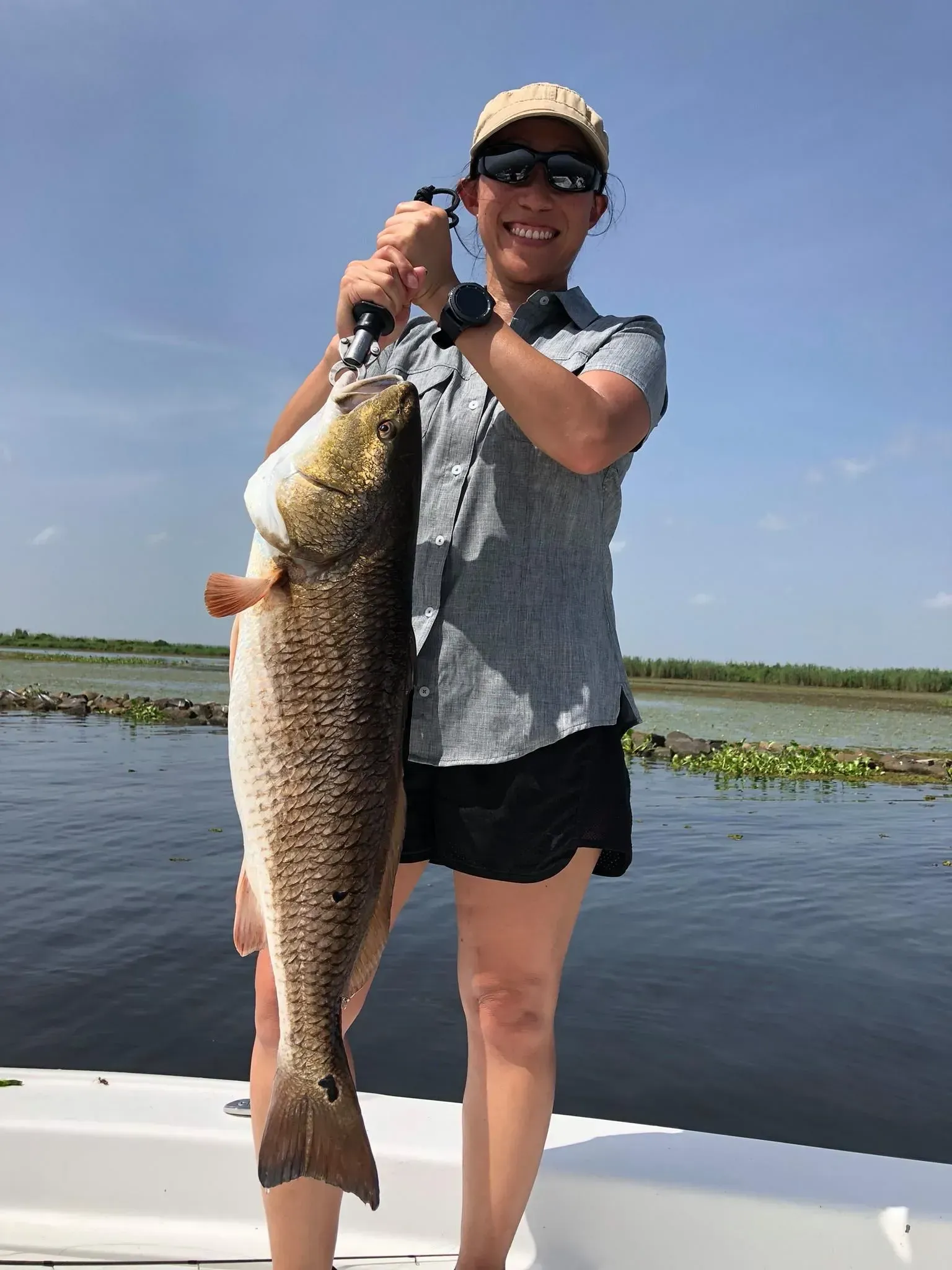 A woman is holding a large fish on a boat.