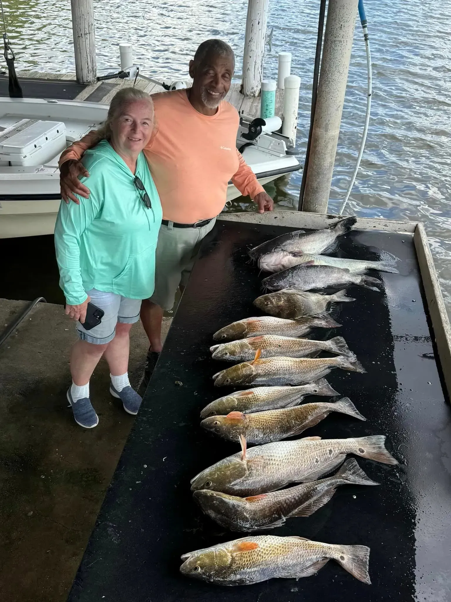 A man and a woman are standing next to a table full of fish.