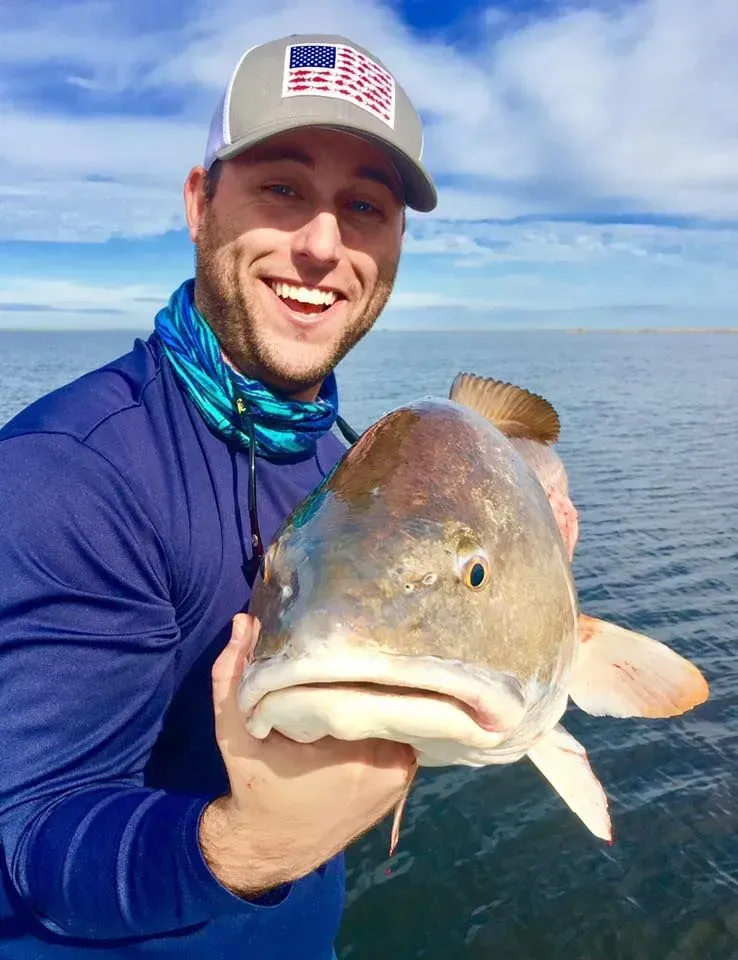 A man is holding a large fish in his hands in the water.