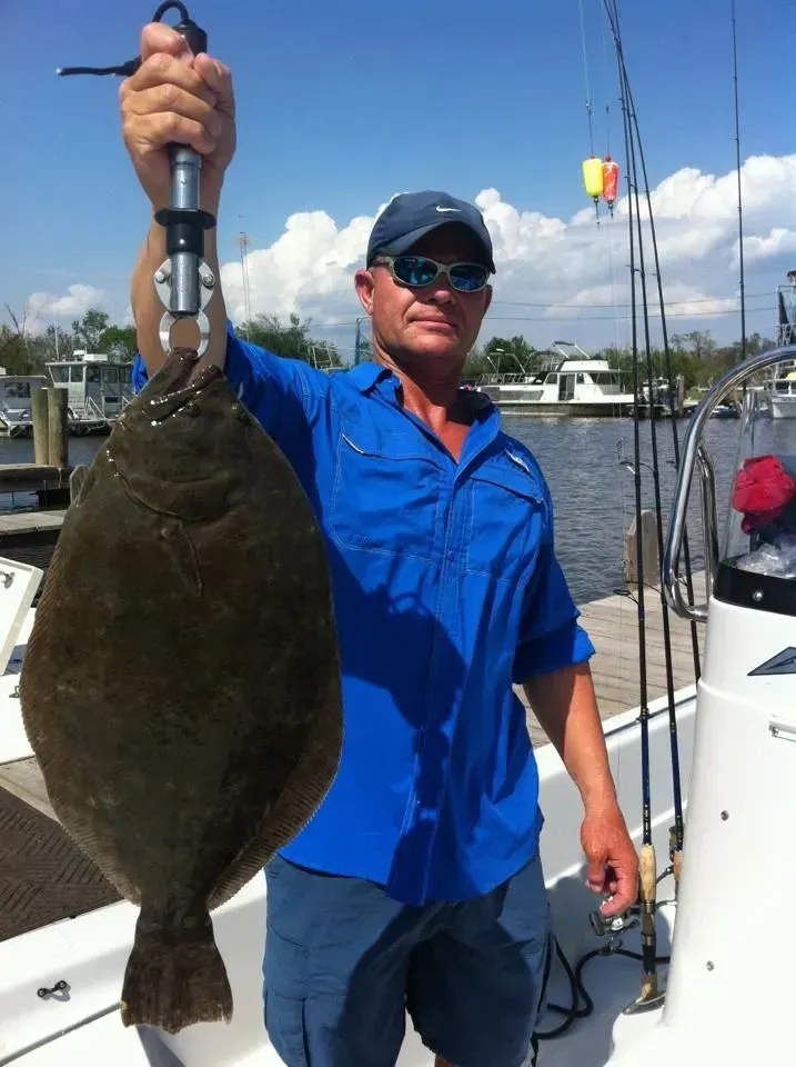 A man in a blue shirt is holding a large fish