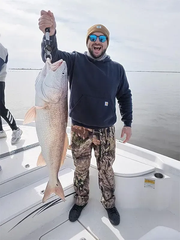 A man is holding a large fish on a boat.