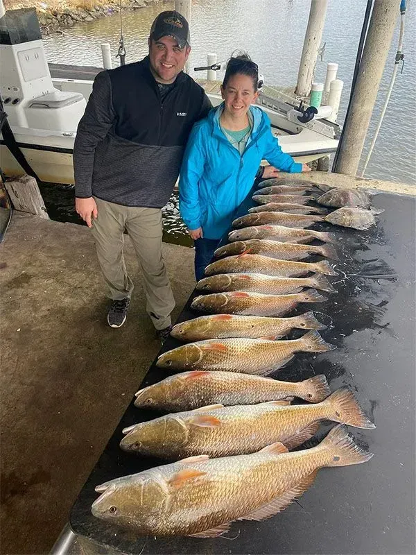 A man and a woman are standing next to a table full of fish.