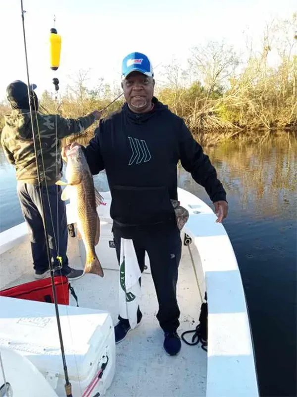 A man is standing on a boat holding a large fish