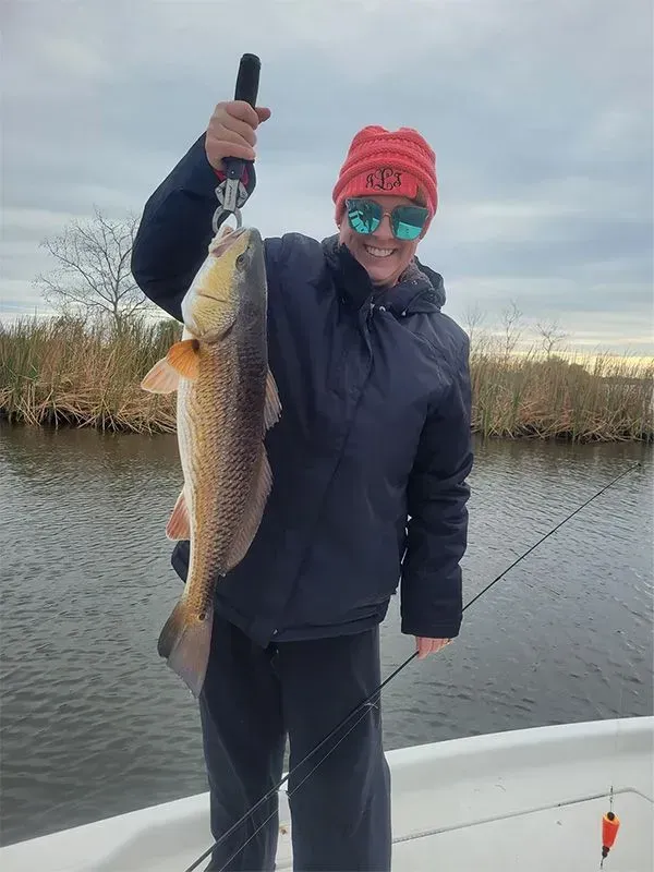 A man is holding a large fish on a boat.