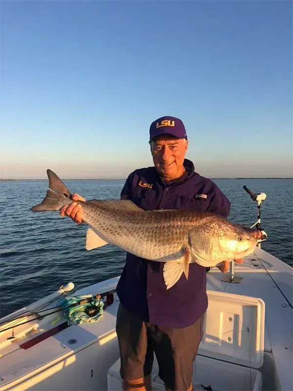 A man is holding a large fish on a boat.