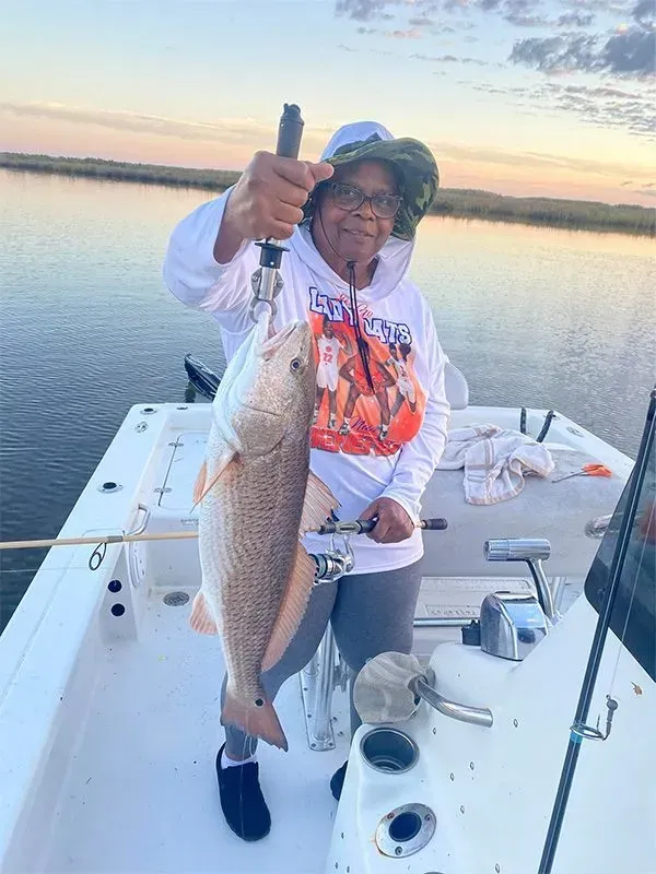 A woman is holding a large fish on a boat.