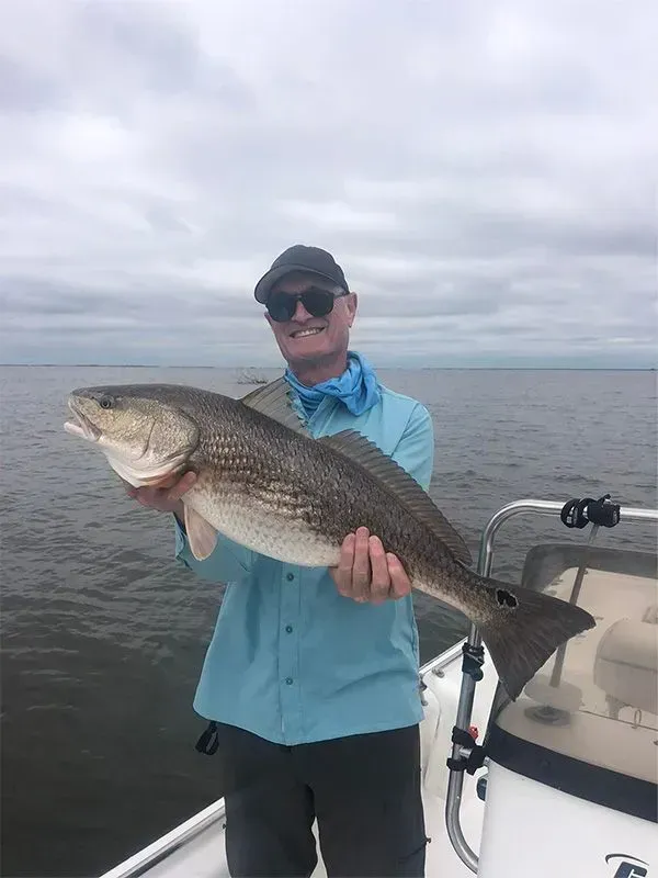 A man is holding a large fish on a boat.