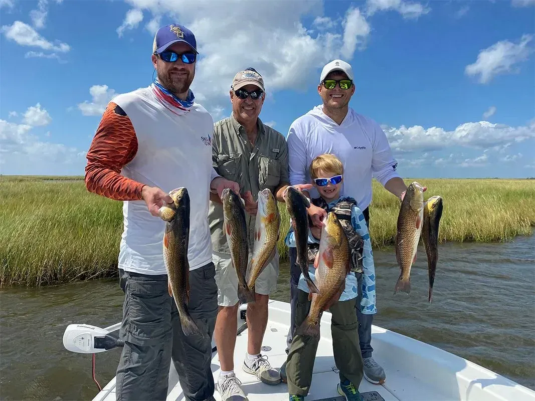 A group of men are standing on a boat holding fish.