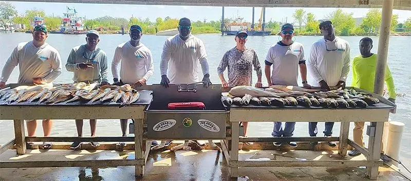 A group of men are standing around a table filled with fish.