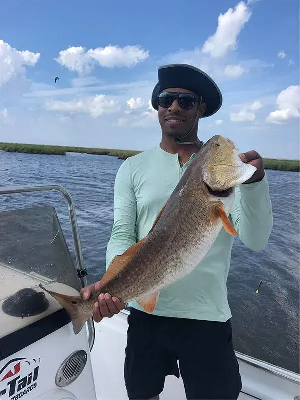 A man is holding a large fish on a boat.