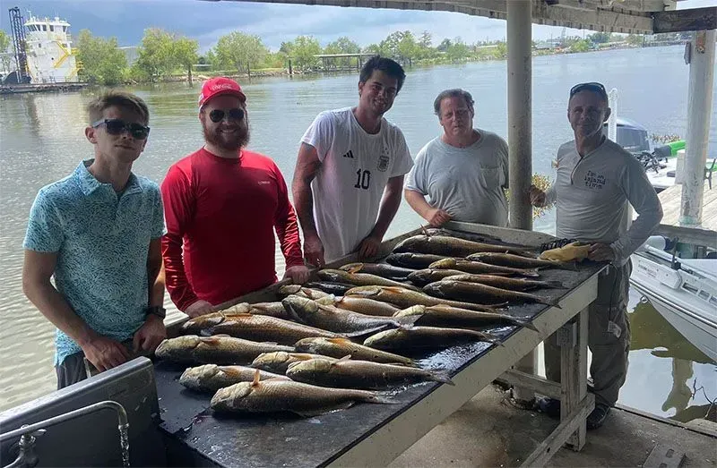 A group of men are standing around a table filled with fish.