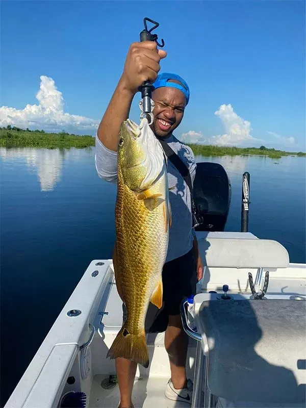 A man is holding a large fish on a boat.