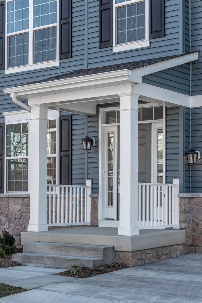 A house with a blue exterior and a white covered porch with a concrete walkway.