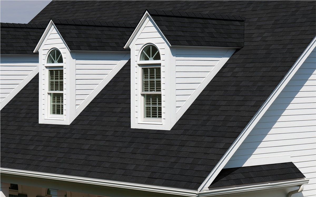 Black shingled roof with white dormer windows on a house with white siding.