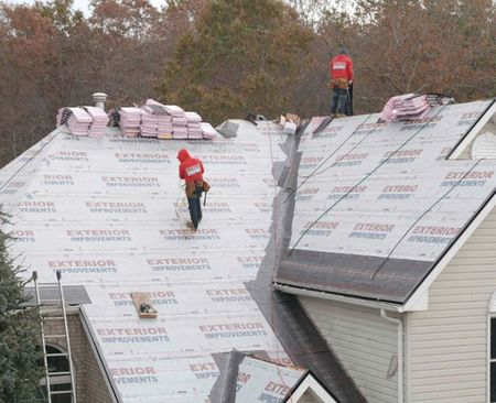 Two men are working on the roof of a house