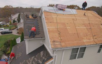 A group of men are working on the roof of a house.