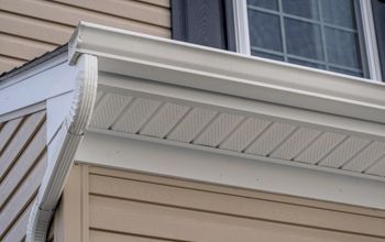 A close up of a gutter on the side of a house.