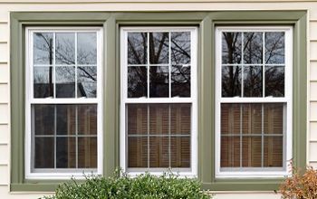 Three windows on the side of a house with green trim