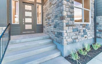 The front door of a house with a stone wall and stairs leading up to it.