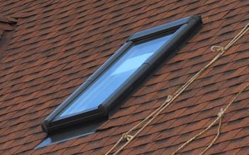 A skylight on top of a brick roof with ropes hanging from it.