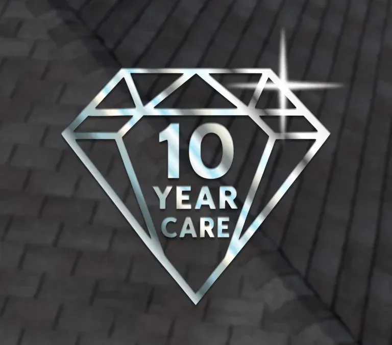 Dark tiled roof with chimney and two skylights against a blue sky.