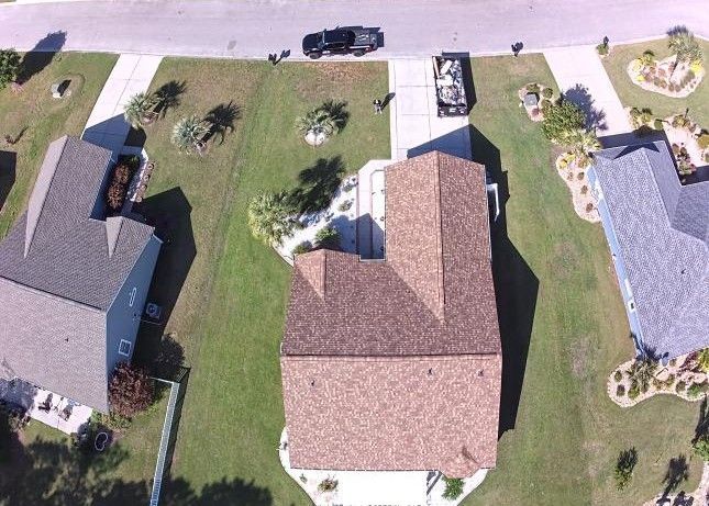 An aerial view of a suburban neighborhood showing three houses and their driveways from directly above.
