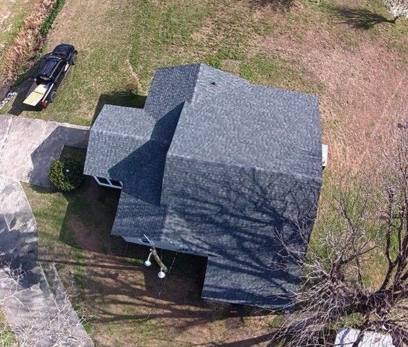 Overhead view of a house with a gray roof and a truck parked nearby on a grassy lawn.
