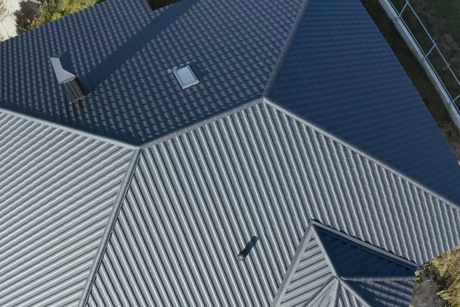 Dark gray metal roof with intersecting sections and a small skylight.