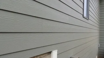 Gray siding on the exterior of a building with horizontal, wood-grain texture.